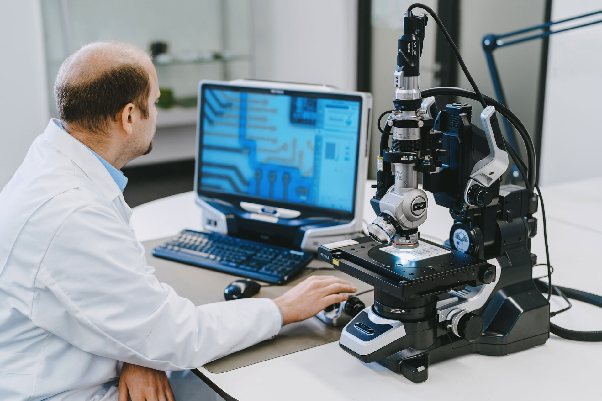 Electronic assemblies Damage analysis Corrosion | © @The Sour Cherry Fotografie - Michaela Curtis A laboratory employee sits at a desk in front of a microscope and carries out a visual damage analysis to determine the contamination of the electronic assembly. | © @The Sour Cherry Fotografie - Michaela Curtis